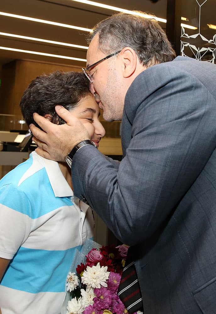 Al-Jazeera journalist Ahmed Mansour, right, kisses his son Mohammed after his arrival at Hamad airport in Doha, Qatar.