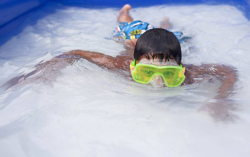 David Kitchens, 8, swims in an inflatable pool in the front yard of his house in Bowling Green, Ky.