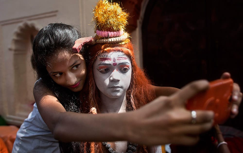 A girl takes a selfie with a boy dressed as Hindu god Shiva at the Kamakhya Hindu temple during the annual Ambubasi festival in Guwahati.