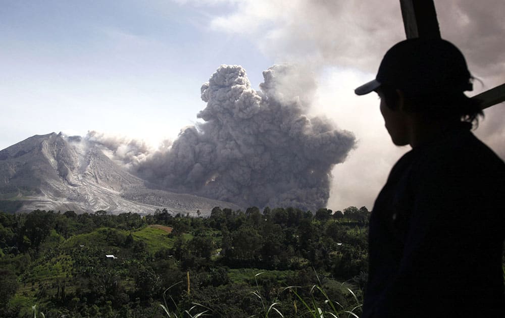 A man watches as Mount Sinabung releases a pyroclastic flow in Tiga Pancur, North Sumatra, Indonesia.