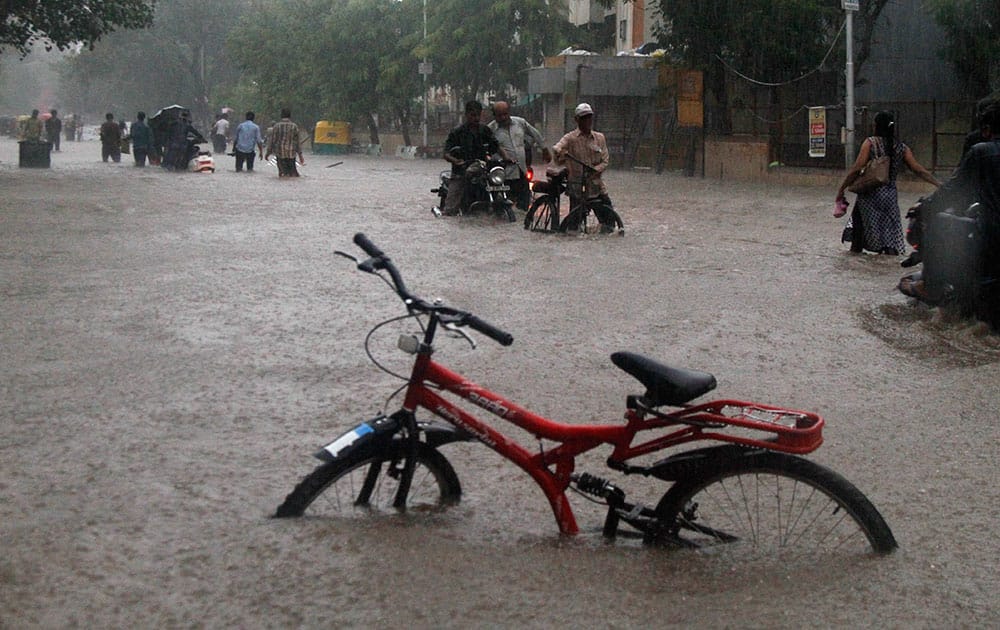 Indians wade through a flooded road during heavy monsoon rain in Ahmadabad, India.