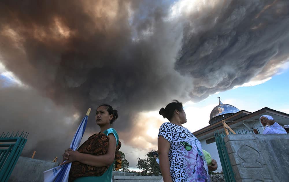 Villagers watch as Mount Sinabung releases volcanic material into the air in Tiga Serangkai, North Sumatra, Indonesia.