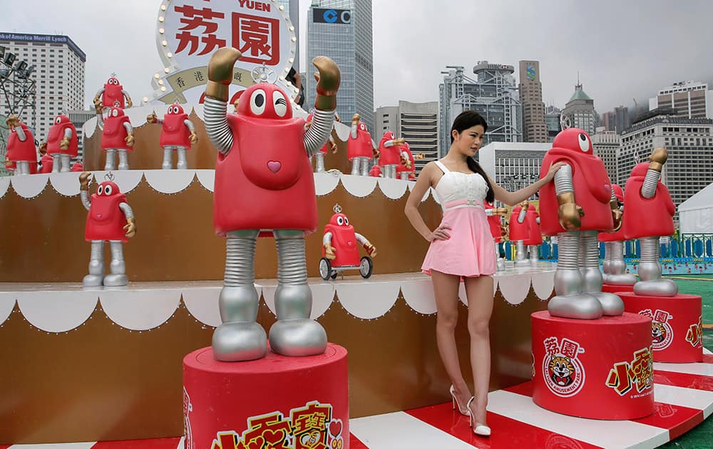 A woman poses with some models of Robocon, a character of Japan's comedy family robot television series, at an amusement park in Hong Kong.