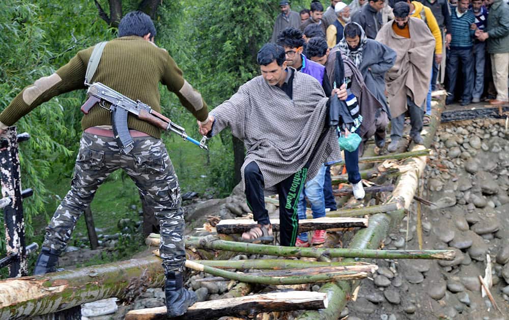 Army and Police personnel rescuing locals from the flood hit area, through a temporary wooden bridge at Nihama, in Kulgam district of South Kashmir.
