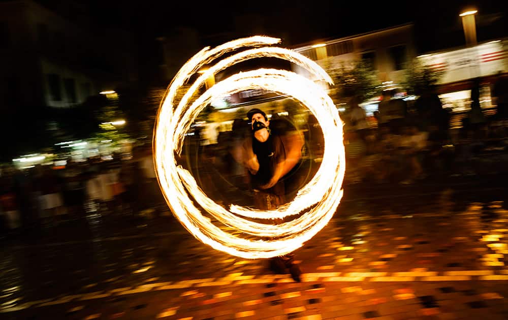 A man juggles fire sticks to earn money in Athens.