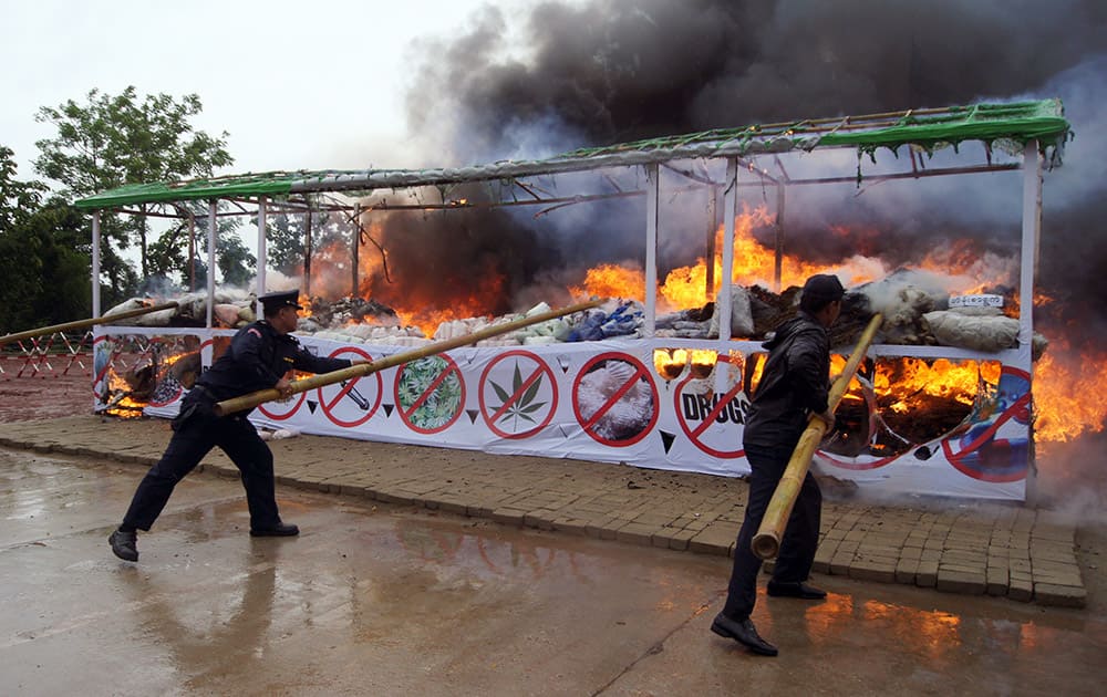 Members of Myanmar fire brigade poke burning narcotic drugs with sticks during a destruction ceremony of seized narcotic drugs in outskirts of Yangon, Myanmar.