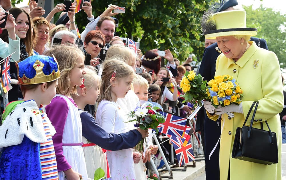 Britain's Queen Elizabeth II, is presented with flowers as she walks across the Pariser Platz near Berlin's landmark Brandenburg Gate, the last day of her state visit to Germany. 