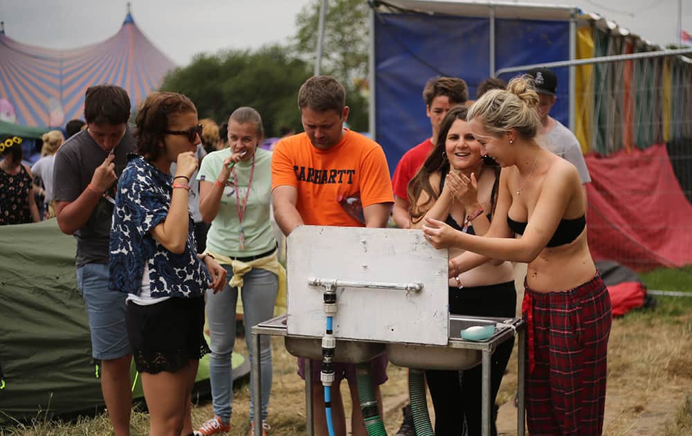 Music fans wash at a water station during Glastonbury Music Festival at Worthy Farm, in Glastonbury, England. 