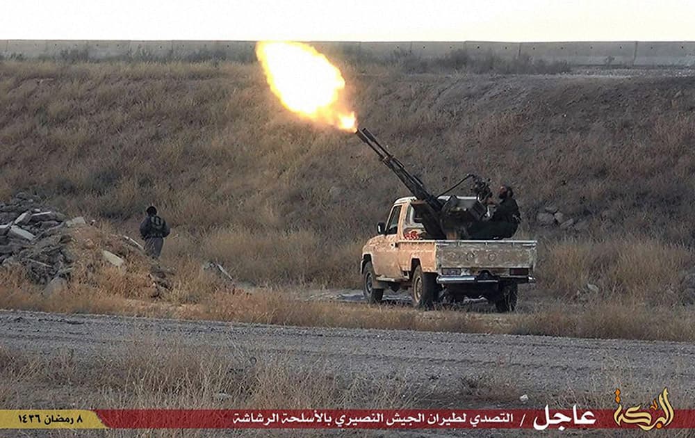 This photo provided by a website of the Islamic State group, shows fighters of the Islamic State group opening fire toward Syrian warplane in the predominantly Kurdish Syrian city of Hassakeh, Syria.