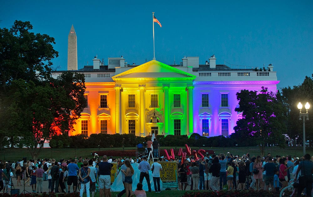 People gather in Lafayette Park to witness the White House being lit up in rainbow colors in commemoration of the Supreme Court's ruling to legalize same-sex marriage, in Washington.