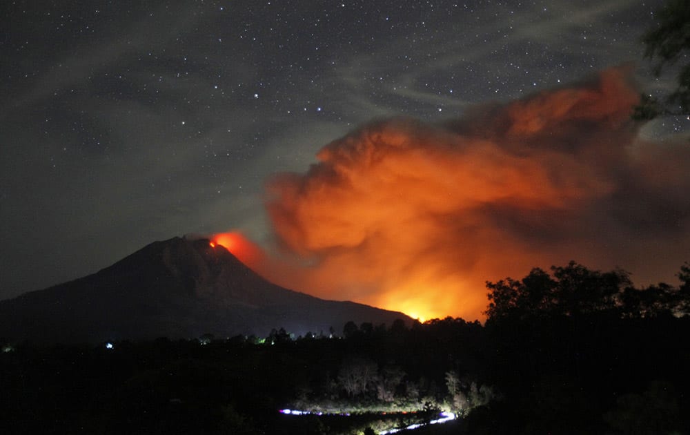 Mount Sinabung spews volcanic materials and hot molten lava from its crater as seen from Tiga Pancur, North Sumatra, Indonesia.