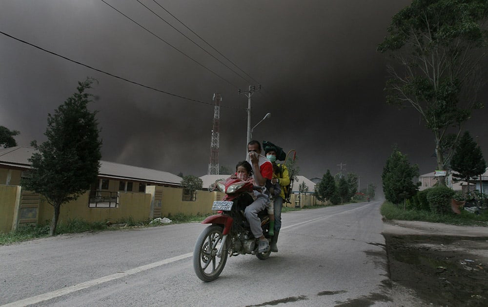 Motorists cover their nose and mouth as volcanic ash from the eruption of Mount Sinabung is blown by the wind at their direction in Sukandebi, North Sumatra, Indonesia