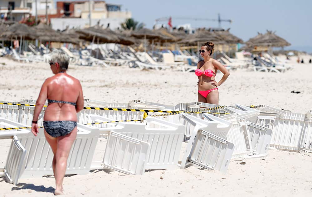 Tourists stand near the scene of a shooting attack on Friday in Sousse, Tunisia. The morning after a lone gunman killed dozens of people at a beach resort in Tunisia, busloads of tourists are heading to the nearby Enfidha-Hammamet airport hoping to return to their home countries.