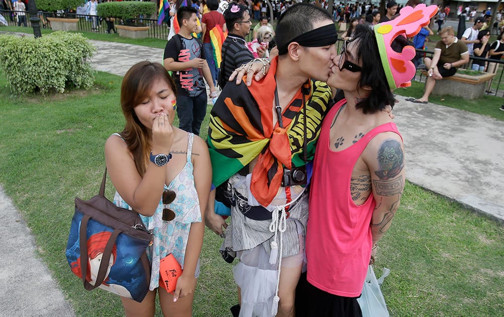 A Filipino LGBT (Lesbians Gays Bisexual and Transgenders), left, pretends to kiss her partner as another couple kiss during a Gay Pride rally in Manila, Philippines to push for LGBT rights and to celebrate the US Supreme Court decision recognizing gay marriages in all U.S. states as a victory for their cause.