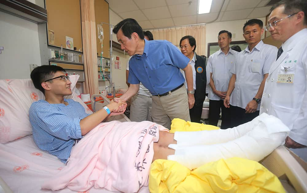 Taiwanese President Ma Ying-jeou shakes hands with a victim injured in an accidental explosion during a music concert, as he visits a local hospital in New Taipei City, Taiwan.