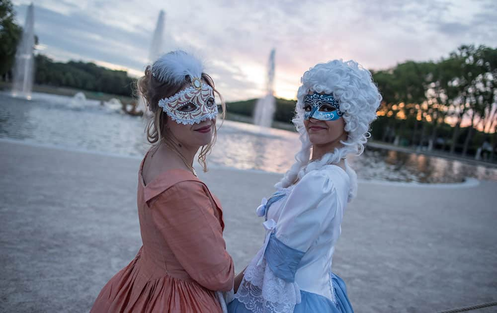 Cloé, left and Lara pose in front a fountain in the gardens of the Versailles castle before the Great Masked Bal, in Versailles, west of Paris.