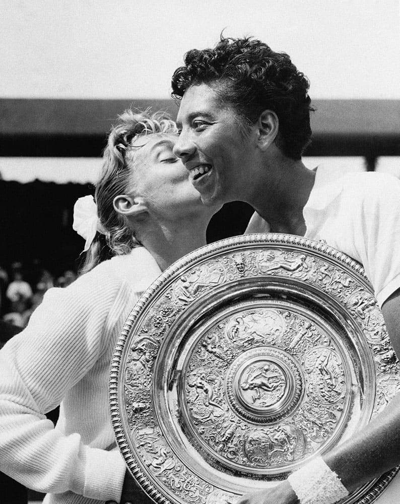 In this July 6, 1957 file photo, Althea Gibson of New York city, holding the large gold plate presented to her as the winner of the Women's Singles Tennis title at the All England Lawn Tennis Championships in Wimbledon, London, is kissed by her opponent, Darlene Hard. Gibson became the first black player, male or female, to win Wimbledon when she defeated fellow American Hard in the final. She ended up with five Grand Slam singles titles, including two Wimbledon crowns, and was twice named The Associated Press’ “Female Athlete of the Year.” Her pioneering didn’t end with tennis. In 1964, Gibson became the first black woman to play in the Ladies Professional Golf Association.