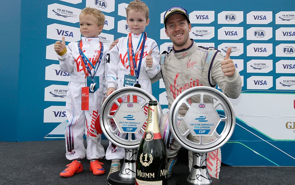 Race winner Britains Sam Bird, driving for Virgin Racing, celebrates with the trophy and his sons, Zak and Flynn, after the Formula E London ePrix auto race in Battersea Park, London.