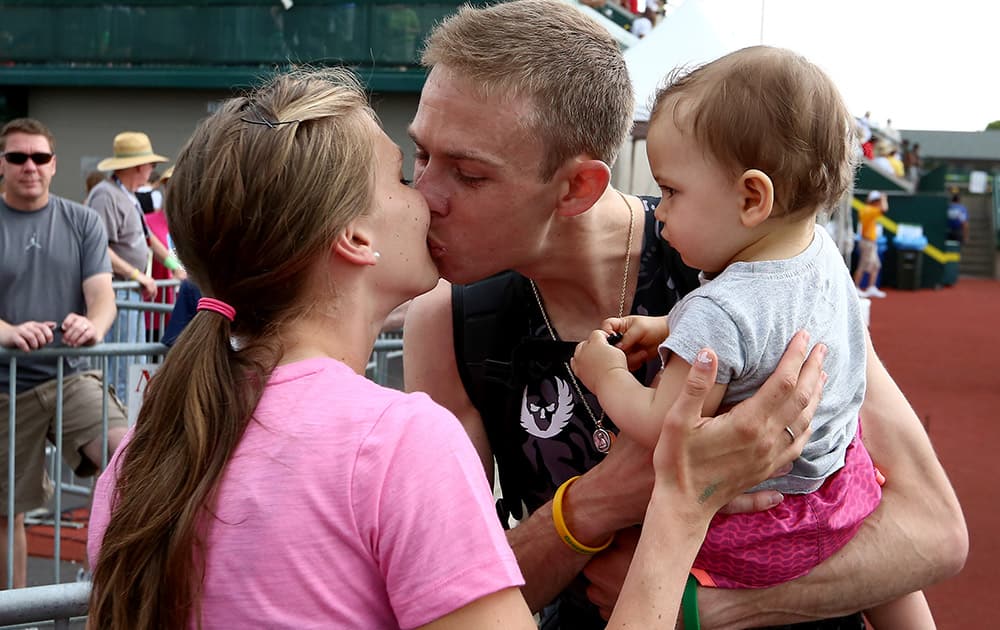 Galen Rupp, center, kisses his wife, Keara Rupp, while holding daughter Emmie after finishing third in the 5000-meter at the U.S. track and field championships in Eugene, Ore.