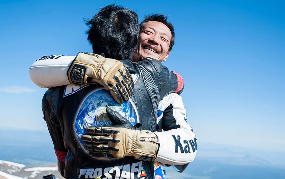 Yoshi Kishimoto, facing camera, is hugged by his friend Yasuo Arai after recording the fastest time for electric-modified motorcycles on top of Pikes Peak during The Broadmoor Pikes Peak International Hill Climb Sunday, June 28 in Cascade, Colo, 2015.