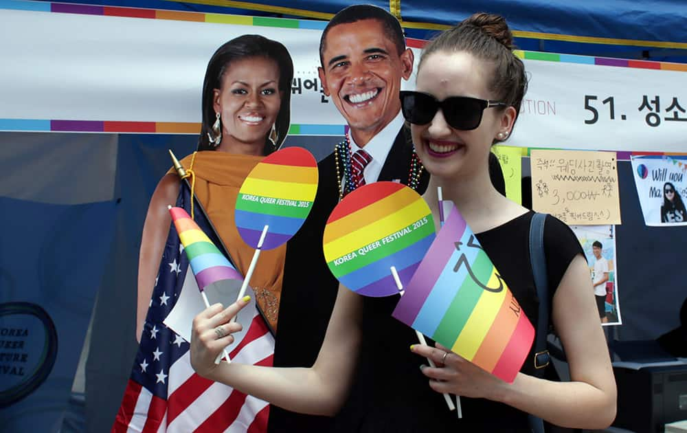 A participant poses for a souvenir photo with cutouts of U.S. President Barack Obama and first lady Michelle Obama during the Korea Queer Festival in Seoul, South Korea.