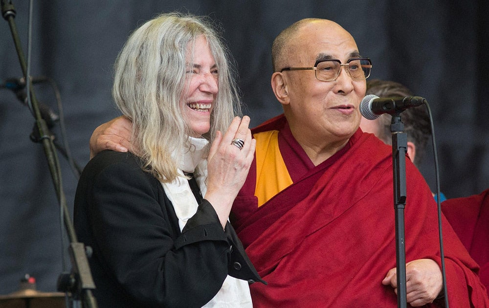 The Dalai Lama speaks to the crowd during singer Patti Smiths, left, performance at the Glastonbury music festival in Glastonbury.