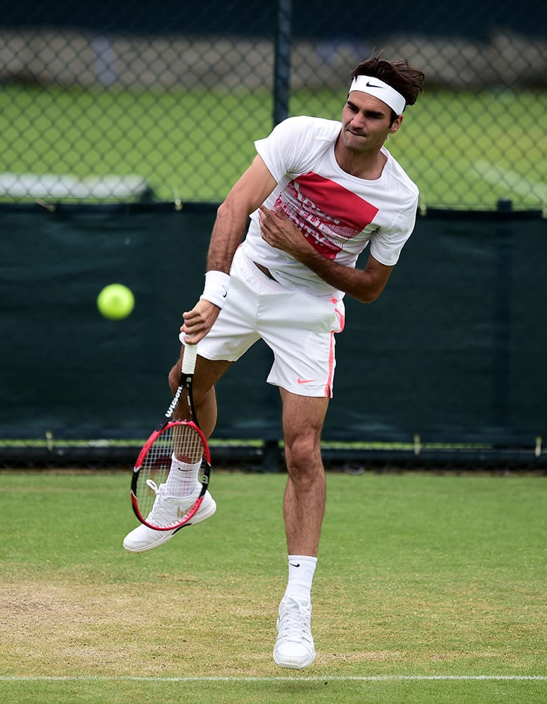 Former champion Roger Federer serves during practice at the Wimbledon Championships at the All England Lawn Tennis and Croquet Club, in Wimbledon London.