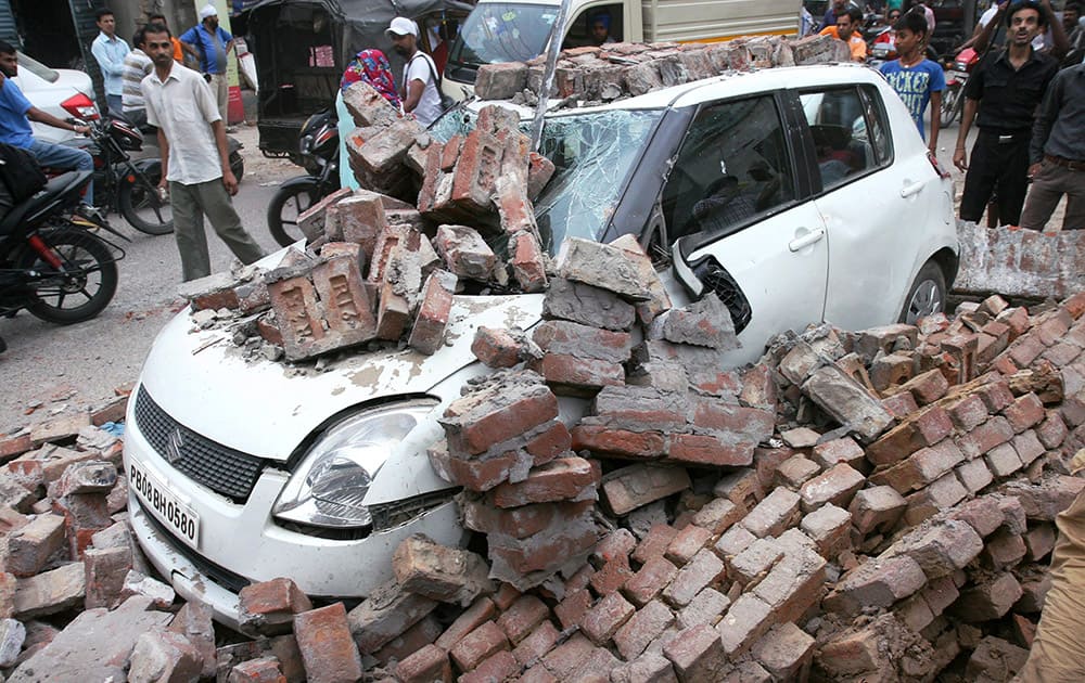 A wall collapses on a car during a wind storm in Jalandhar, Punjab.