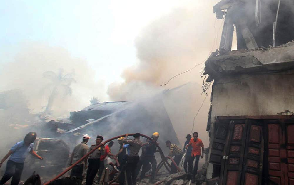 Firefighters and military personnel work to extinguish the fire at the site where an air force cargo plane crashed in Medan, North Sumatra, Indonesia.  An Indonesian air force Hercules C-130 plane with 12 crew aboard has crashed into a residential neighborhood in the country's third-largest city Medan.