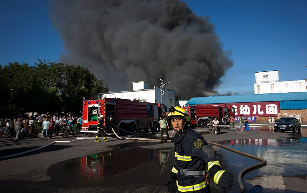 A firemen urges people to move away from a fire at a lumberyard in the south side of Beijing, China.