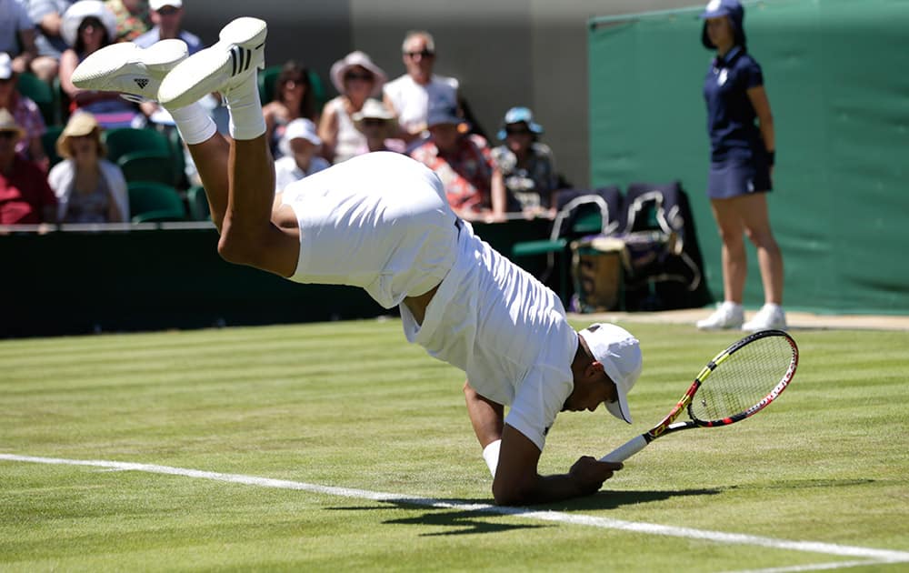 Jo-Wilfried Tsonga of France tumbles after playing a shot to Gilles Muller of Luxembourg during their singles first round match at the All England Lawn Tennis Championships in Wimbledon, London.