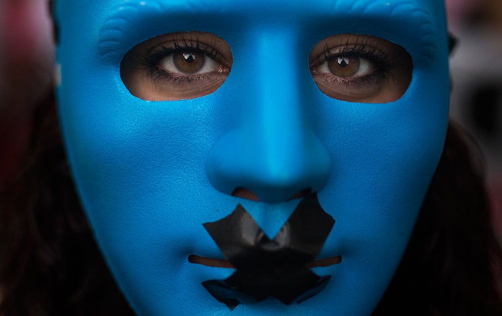 A protestor wears a mask with a gag as she marches against the Public Security Law in Madrid, Spain.