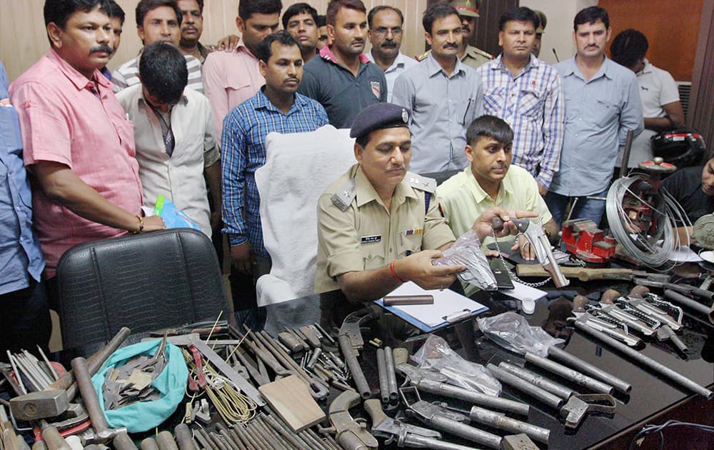 Police officers showing illegal weapons recovered after bust of illegal arms factory in Meerut.