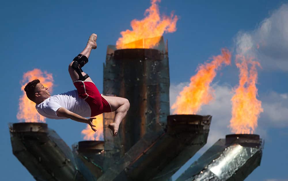 Adam Menzies, an instructor and performer with the Vancouver Circus School, does a flip in front of the Olympic cauldron during Canada Day celebrations, in Vancouver, British Columbia. 