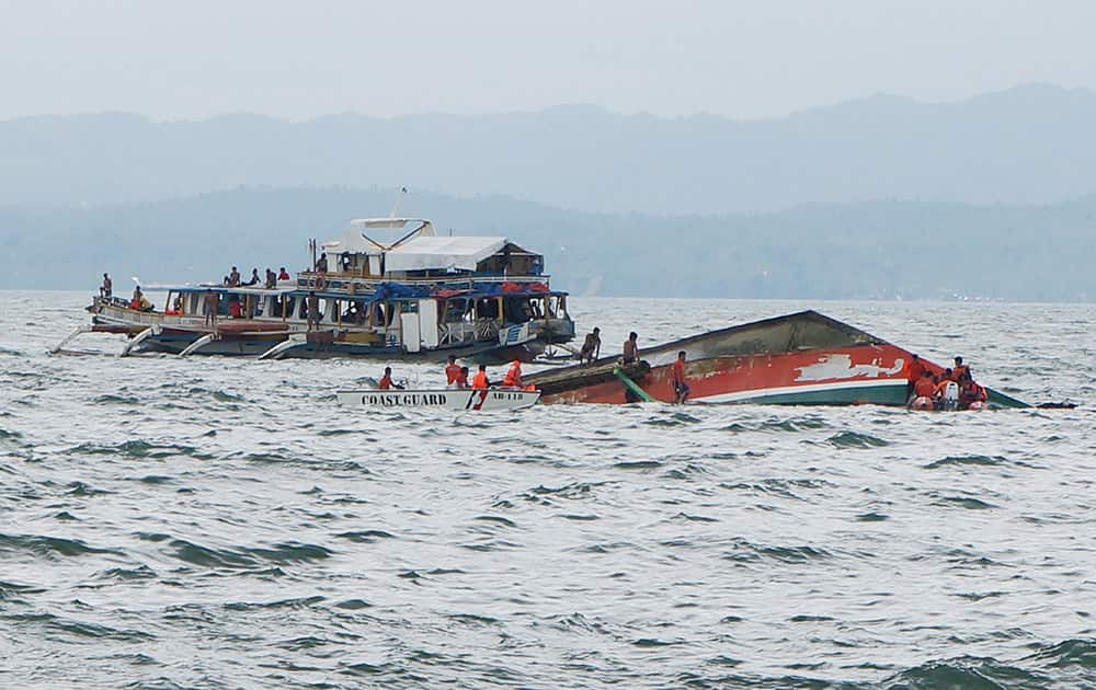 Rescuers help passengers from a capsized ferry boat, right, in Ormoc city on Leyte Island, Philippines.