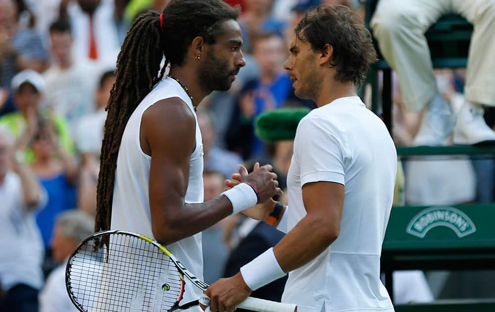 Dustin Brown of Germany shakes hands at the net with Rafael Nadal of Spain, after defeating him during the singles match, at the All England Lawn Tennis Championships in Wimbledon, London.