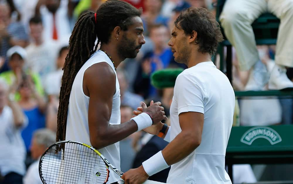 Dustin Brown of Germany shakes hands at the net with Rafael Nadal of Spain, after defeating him during the singles match, at the All England Lawn Tennis Championships in Wimbledon, London.