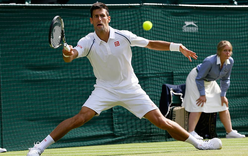 Novak Djokovic of Serbia returns a ball to Bernard Tomic of Australia during their singles match at the All England Lawn Tennis Championships in Wimbledon, London.