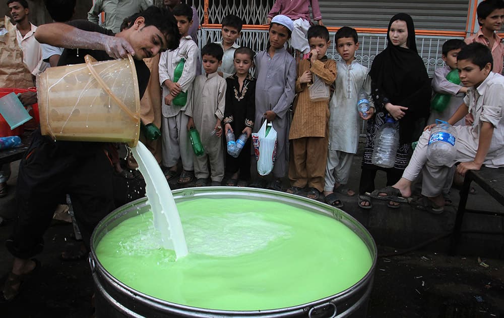 Pakistani children wait to receive milk mixed with fruit juice to break the day's fast that many Muslims practice during the month of Ramadan in Karachi, Pakistan.