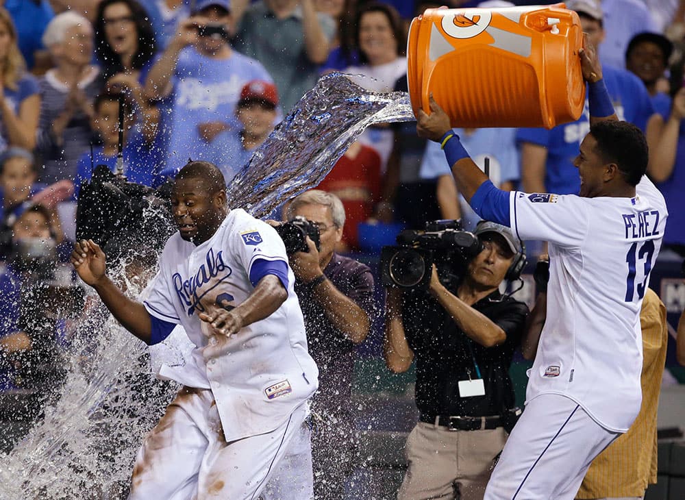 Kansas City Royals' Lorenzo Cain, left, tries to dodge a cooler of water being emptied by teammate Salvador Perez (13) following a baseball game against the Minnesota Twins at Kauffman Stadium in Kansas City, Mo.