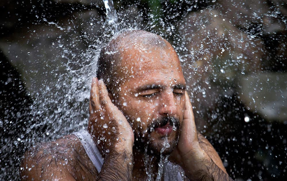 A Pakistani man cools himself off under a water supply line, after temperature reached 39 degrees Celsius (102.2 Fahrenheit), in Islamabad, Pakistan.