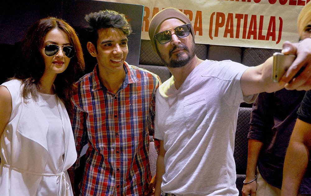 Bollywood actor Jimmy Shergill and actress Surveen Chawla take a selfie with a fan at an event to promote their upcoming movie in Patiala.