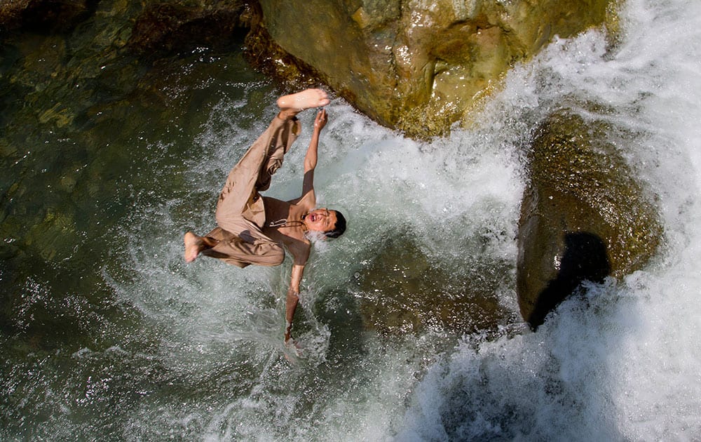 A Kashmiri boy jumps into a stream as boys cool off on a hot afternoon near Wangath, Some 48 kilometers (30 miles) northwest of Srinagar, India.