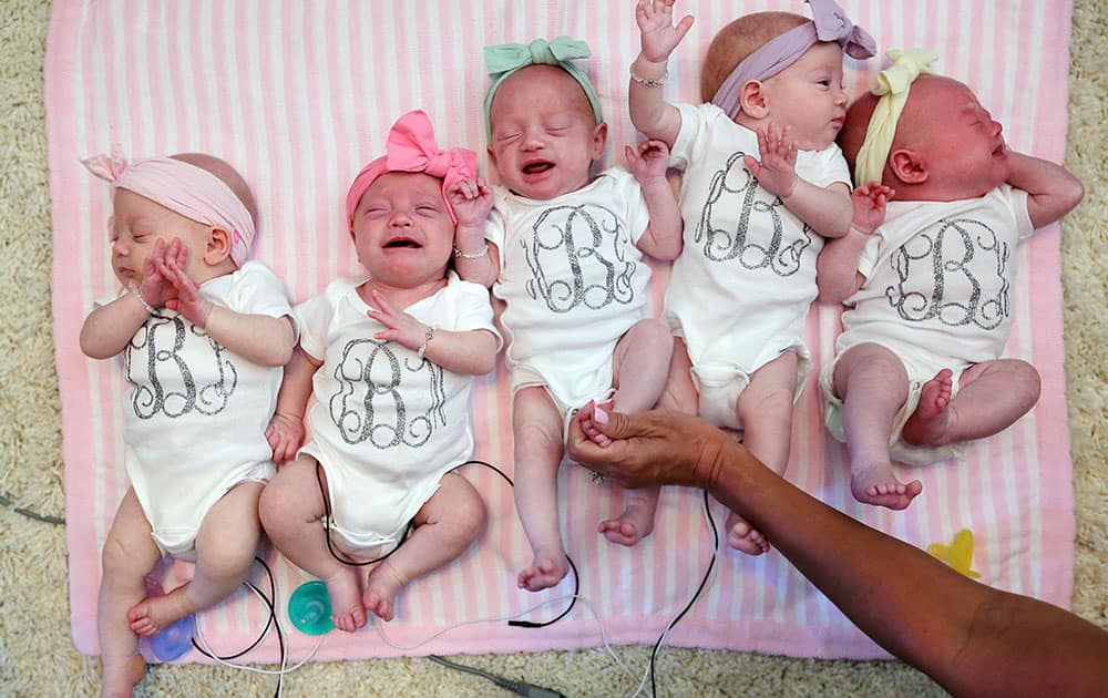 Ava Lane, Olivia Marie, Hazel Grace, Riley Paige, and Parker Kate Busby lie next to one another at home with parents Danielle and Adam Busby in League City, Texas.