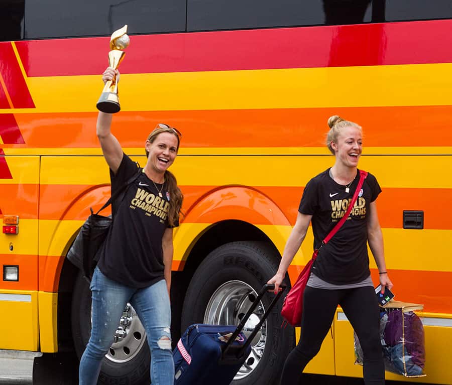 The U.S. women's national soccer team captain Christie Rampone, left, holding the trophy, and her teammate Becky Sauerbrunn arrive at Los Angeles International Airport.