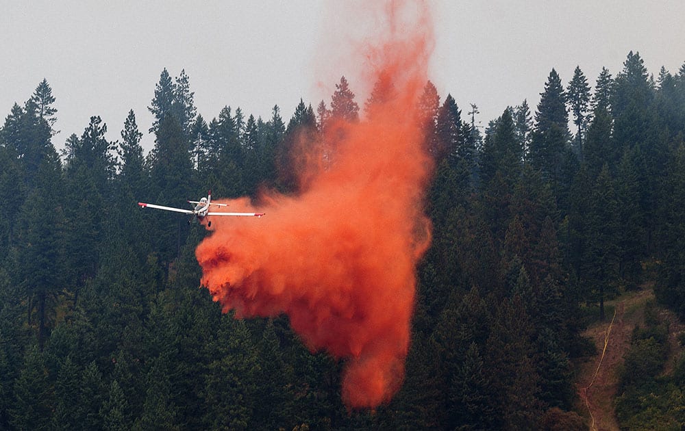An airplane used in air support efforts drops fire retardant near the perimeter of the Cape Horn fire in Bayview, Idaho.