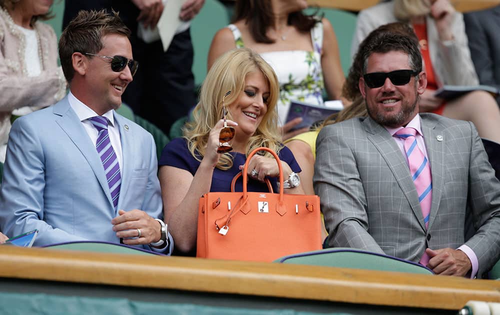 Golfer Ian Poulter, his wife Katie and fellow golfer Lee Westwood, take their seats prior to the start of the singles match between Serena Williams of the United States and Venus Williams of the United States, at the All England Lawn Tennis Championships in Wimbledon, London.