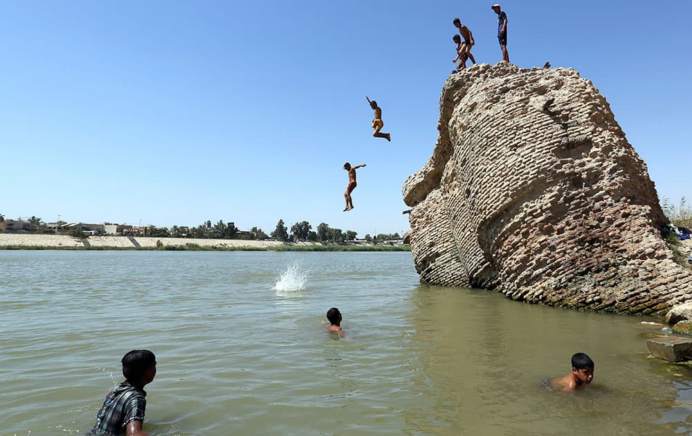 Children jump off the ruin of an old building into the Tigris River to beat the heat in Baghdad, Iraq.