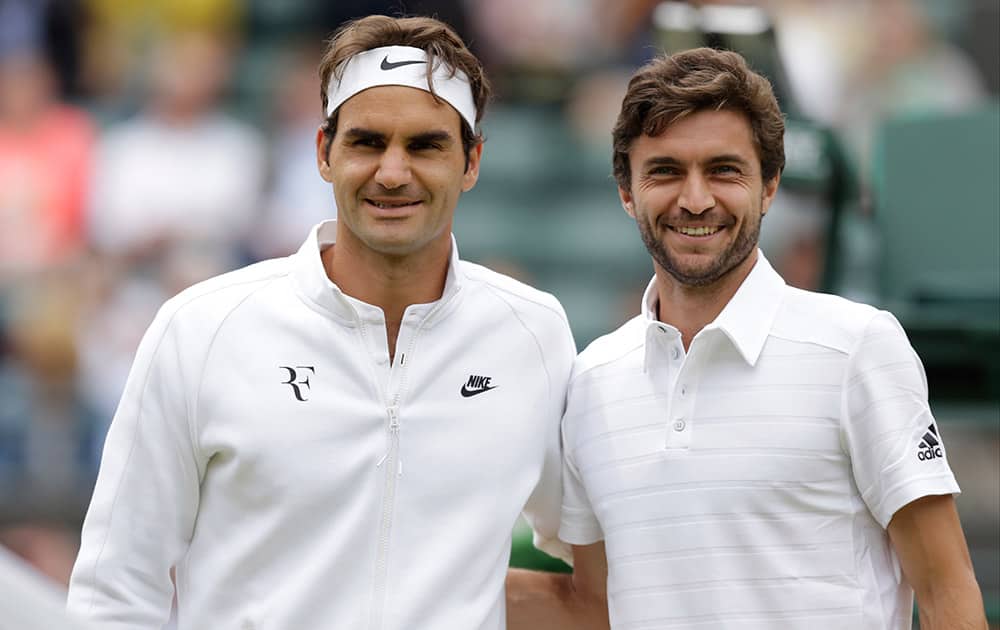 Roger Federer of Switzerland and Gilles Simon of France pose for a photograph ahead of the men's quarterfinal singles match at the All England Lawn Tennis Championships in Wimbledon, London.