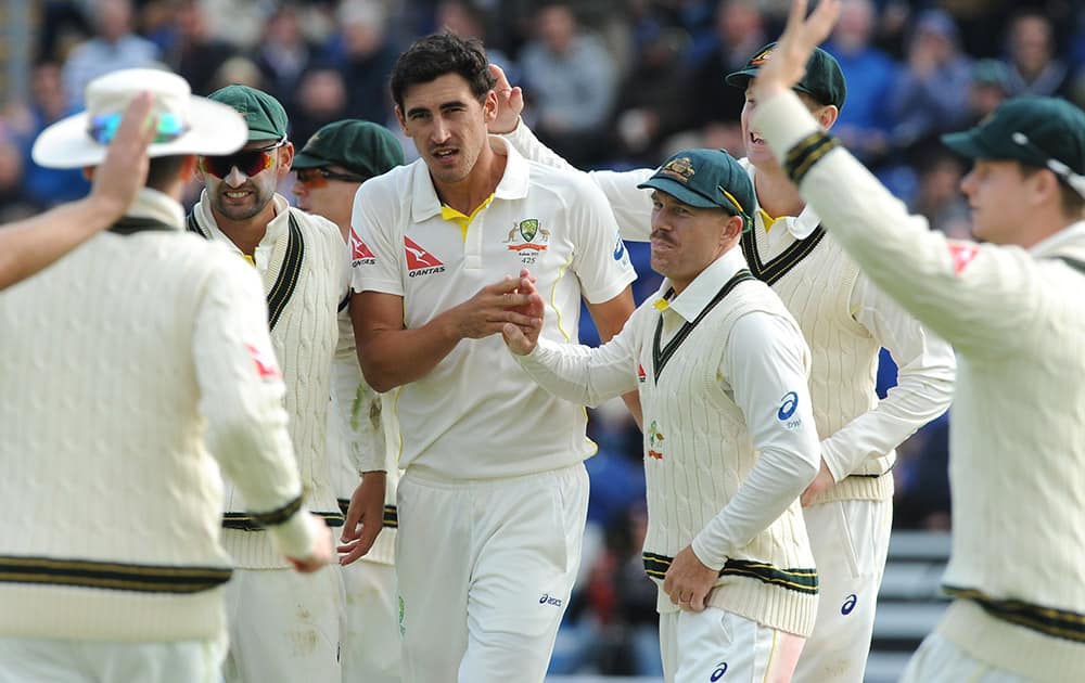 Australia’s Mitchell Starc is congratulated by teamates after bowling England's Joe Root caught Shane Watson for 134 runs during day one of the first Ashes Test cricket match, in Cardiff, Wales.